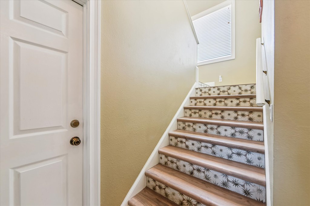 Wooden staircase with starburst-patterned risers and a white handrail beneath a high window.