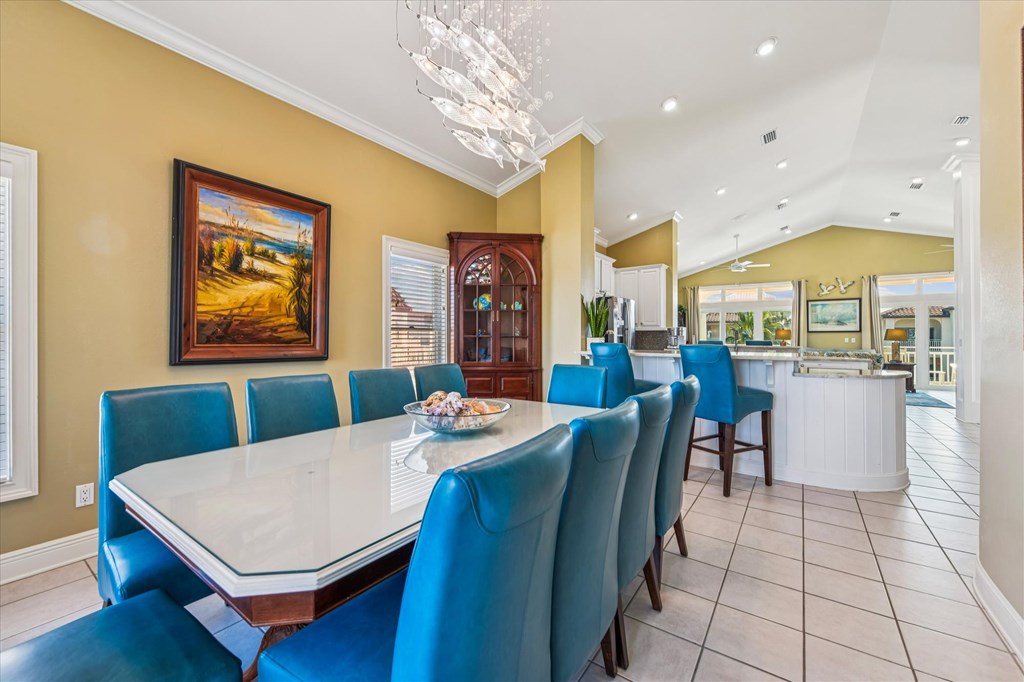 Dining room with a white table, blue chairs, and an open kitchen.