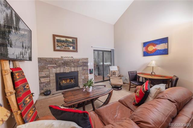 Living room with a stone fireplace, leather sectional, and colorful Southwestern-style accents.