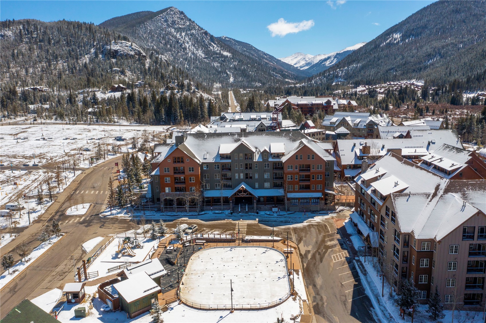 Keystone condominium complex and outdoor ice rink beneath snow-covered mountains.