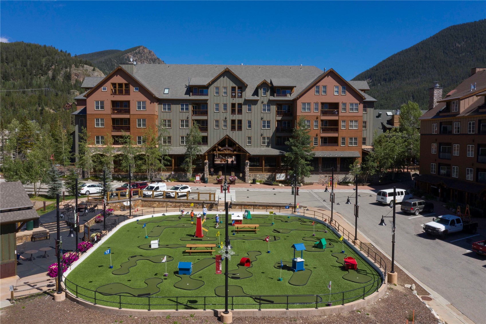 Mountain condominium building behind a miniature golf course, with forested mountains in the background.
