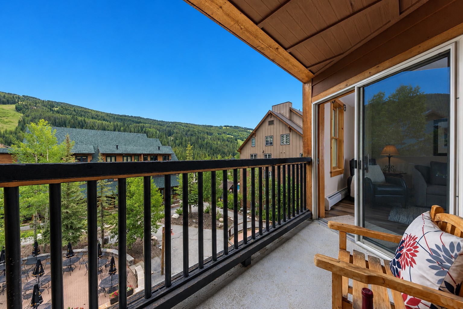 Covered wooden balcony overlooking neighboring buildings and a forested mountain slope