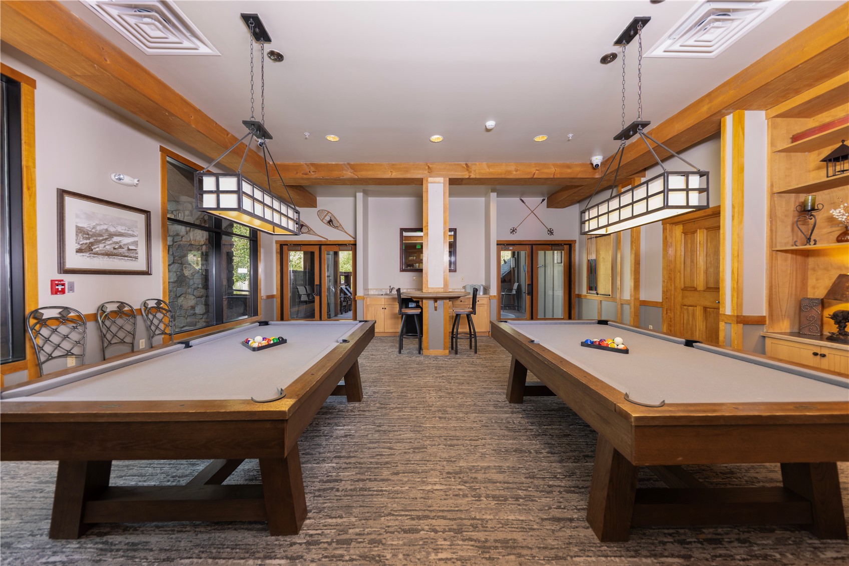 Recreation room with two pool tables, a central counter, and exposed timber beams.