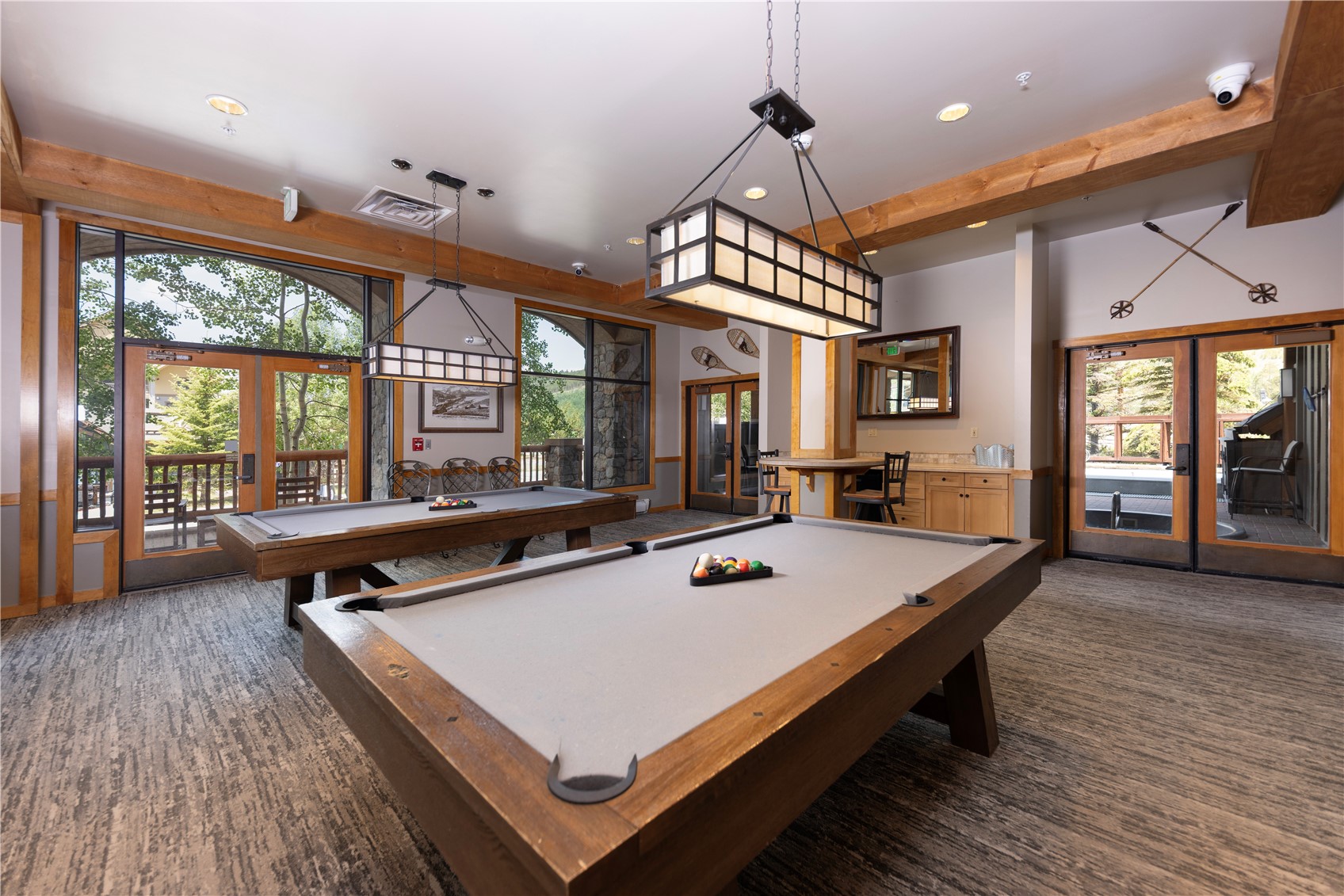 Billiards room with two pool tables and glass doors opening to a deck.