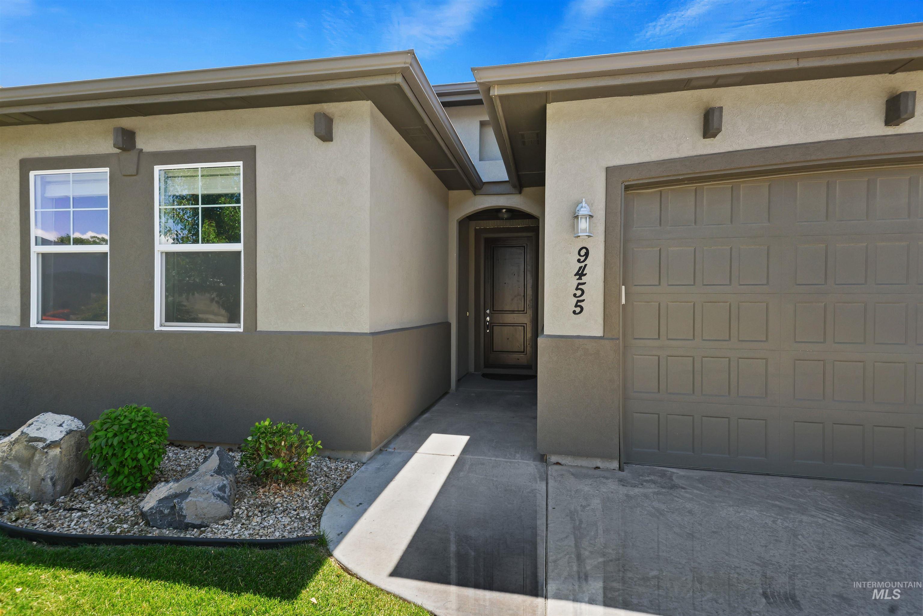 Home exterior with recessed entry, attached garage, and rock landscaping.