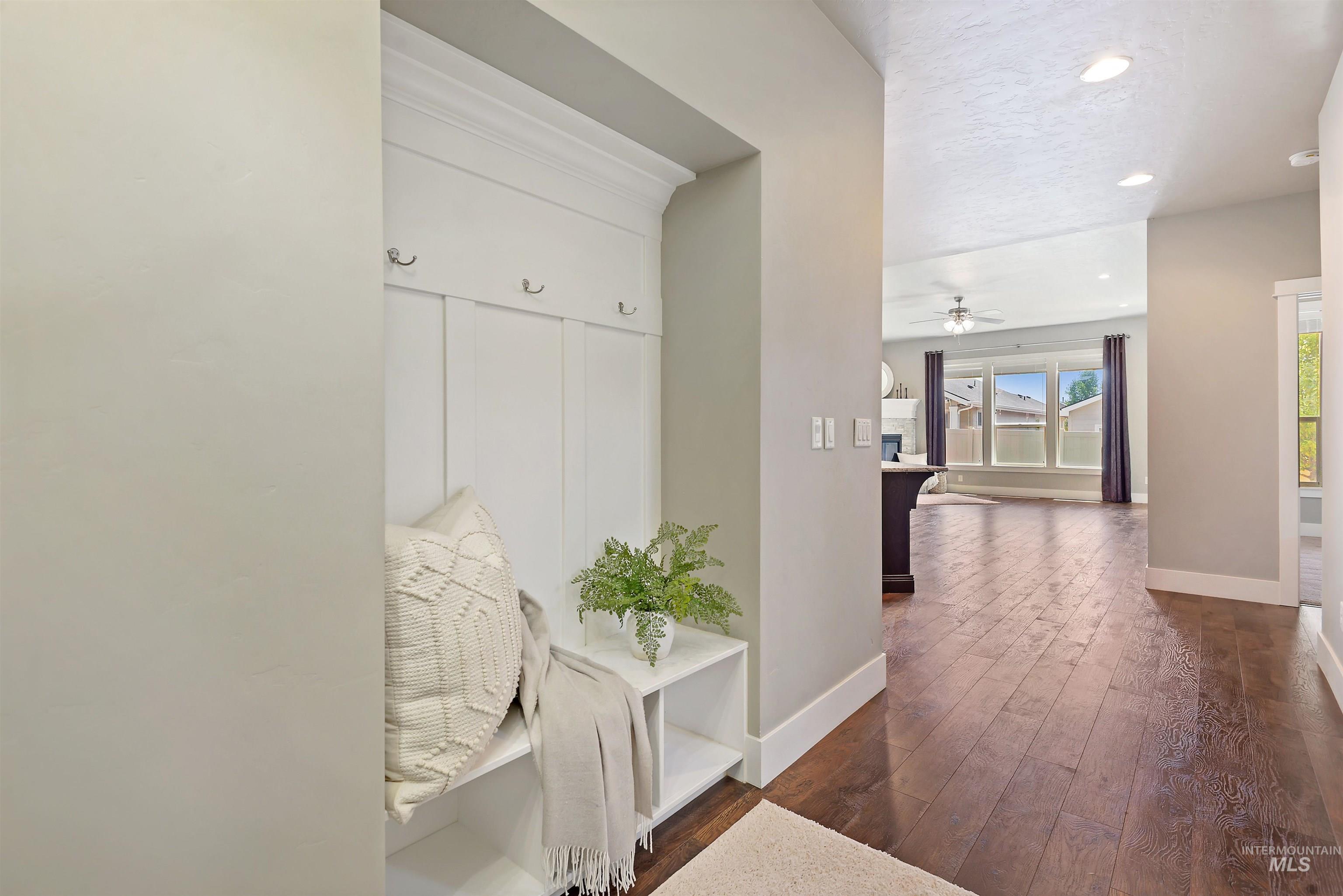 Entry hallway with built-in bench and coat hooks opens to a bright living area with dark wood floors.