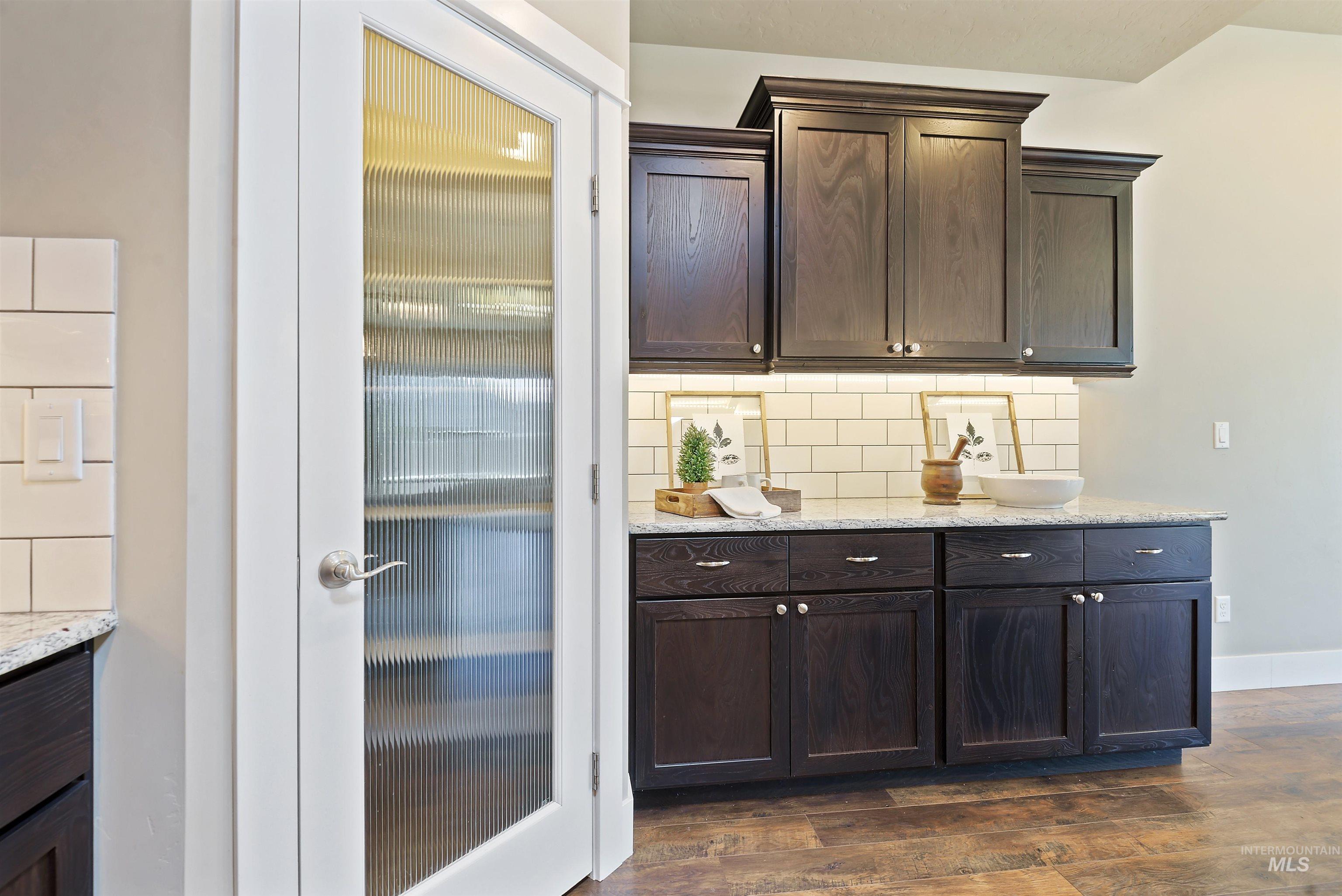 Bathroom vanity with dark wood cabinets, two vessel sinks, and a ribbed-glass door.