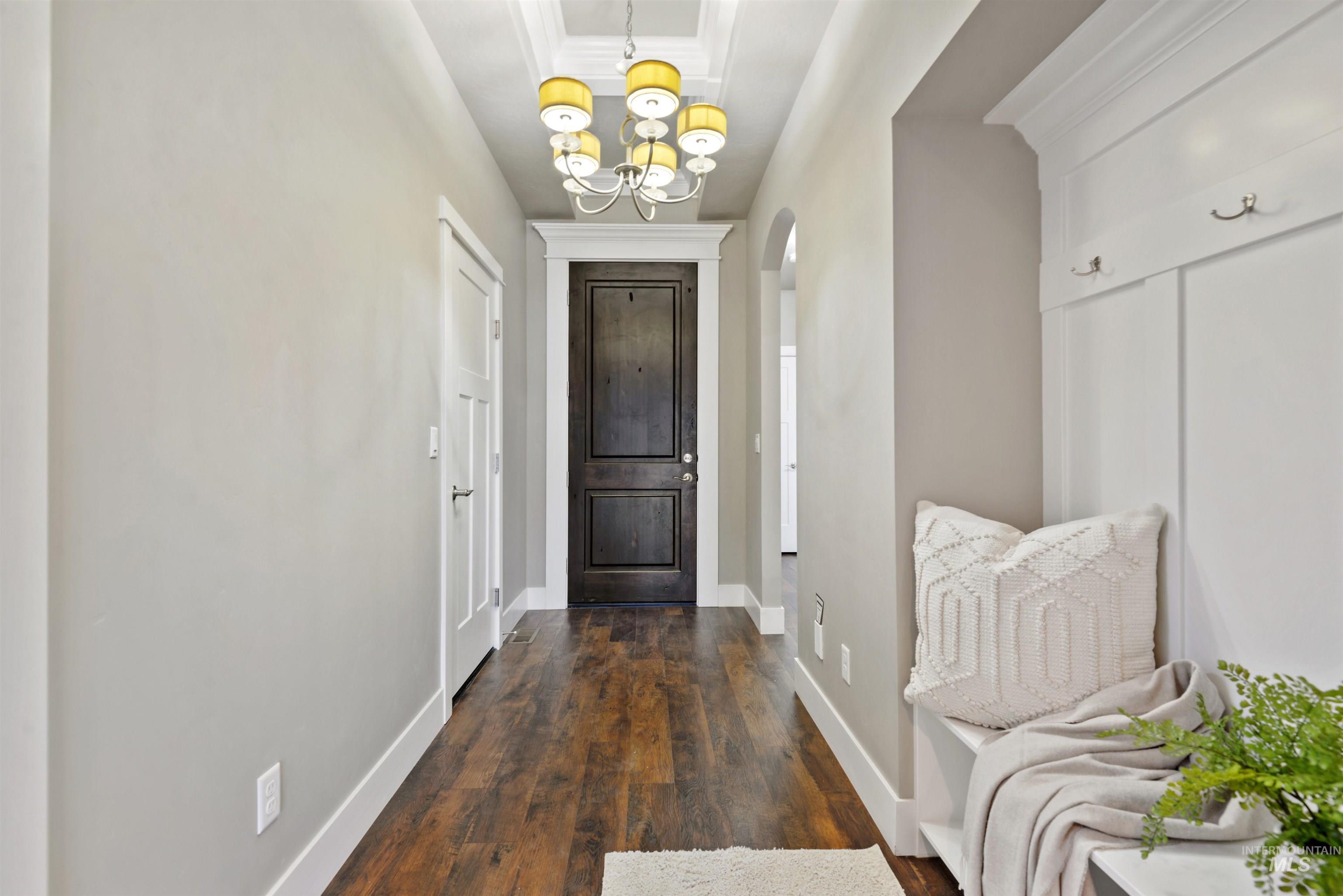 Entry hallway with dark wood floors, a paneled front door, chandelier, and built-in bench.