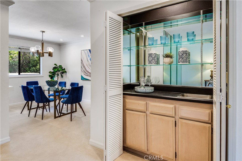 Dining room beside a built-in wet bar with glass shelves and blue upholstered chairs.