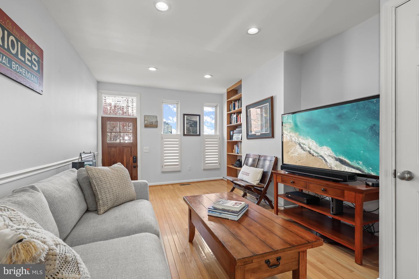 Living room with hardwood floors, gray sectional, wooden coffee table, and built-in bookcase.