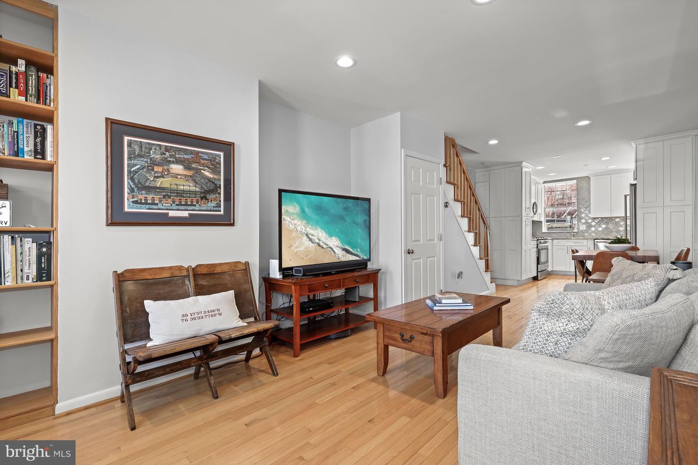 Living room with hardwood floors, a gray sectional, wooden furniture, and an open view into the kitchen.