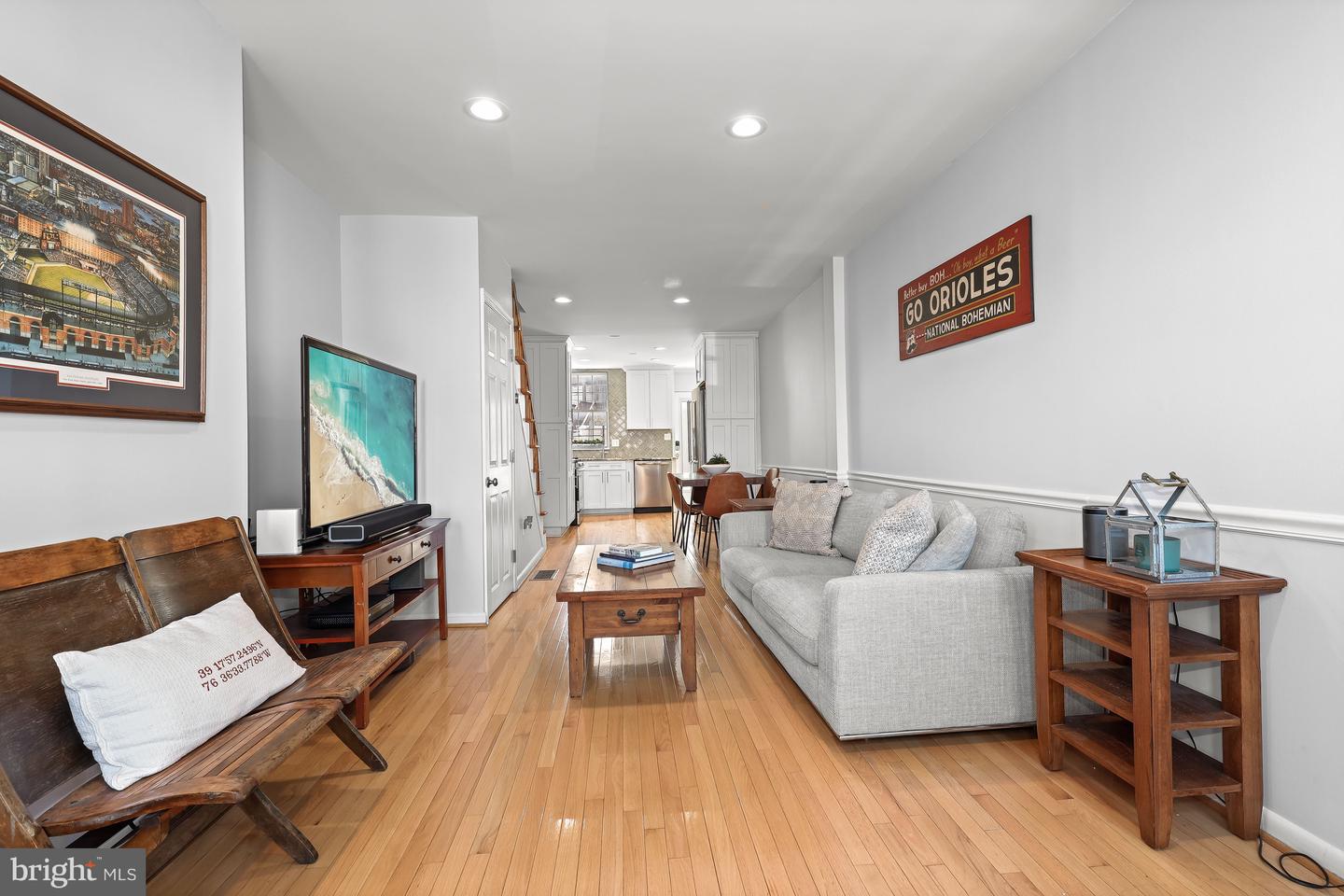 Living room with a gray sofa, hardwood floors, and an open view to the kitchen.