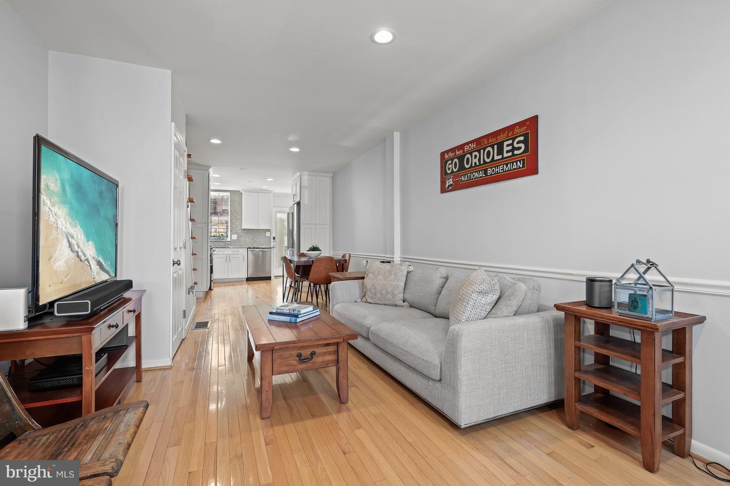 Living room with hardwood floors, a gray sofa, and an open view into the kitchen.