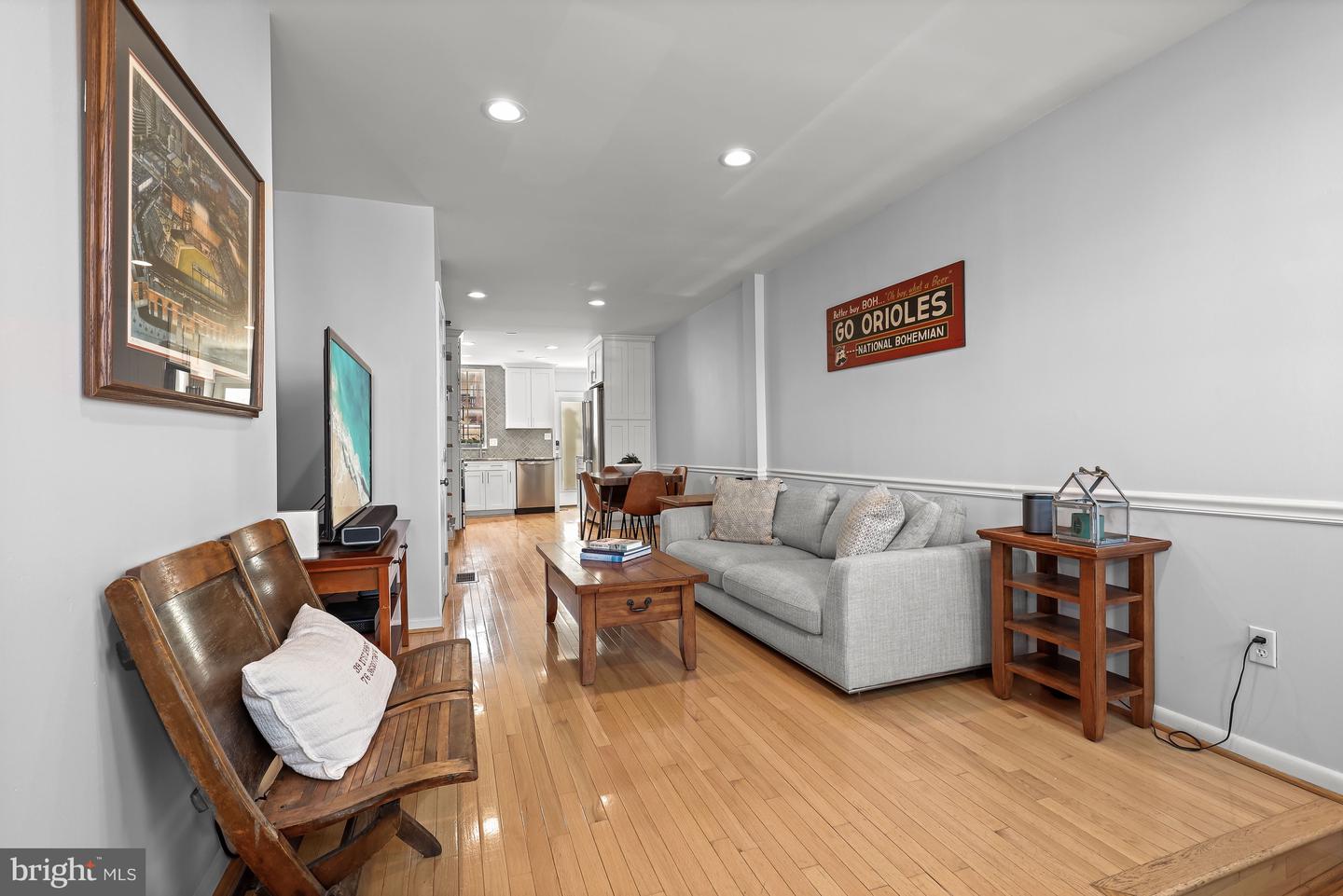 Living room with hardwood floors, gray sofa, wooden furniture, and a Go Orioles sign.