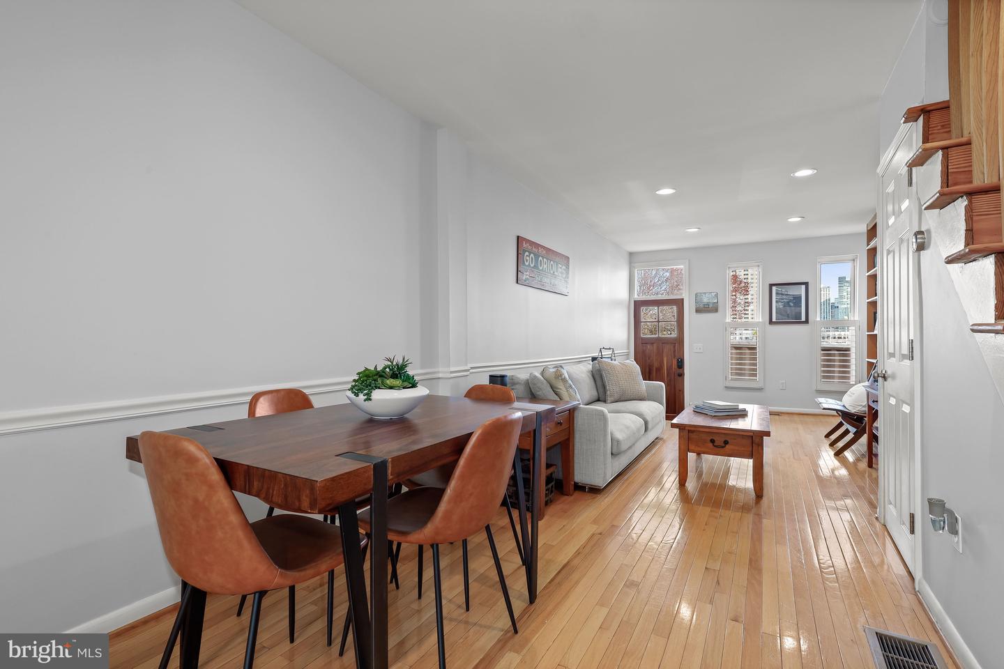 Furnished living and dining room with hardwood floors, a gray sofa, and a dark wood dining table.