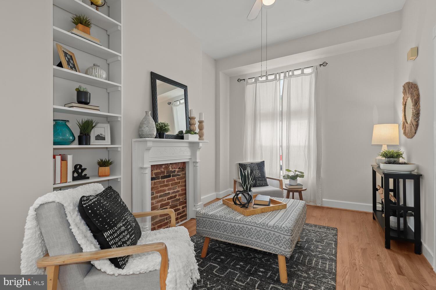 Living room with a brick fireplace, built-in shelves, and neutral seating.