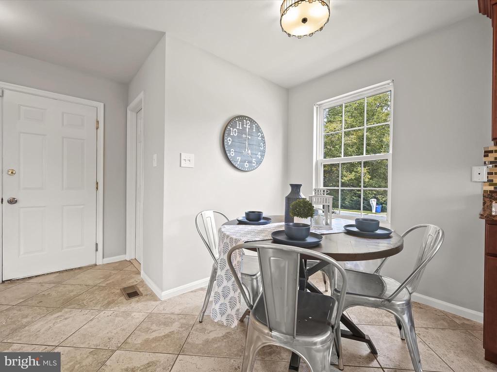 Dining area with a set round table, metal chairs, and a large window overlooking trees.