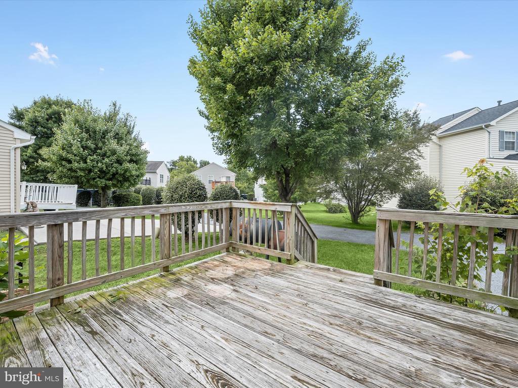 Wooden backyard deck overlooking a lawn and mature trees.