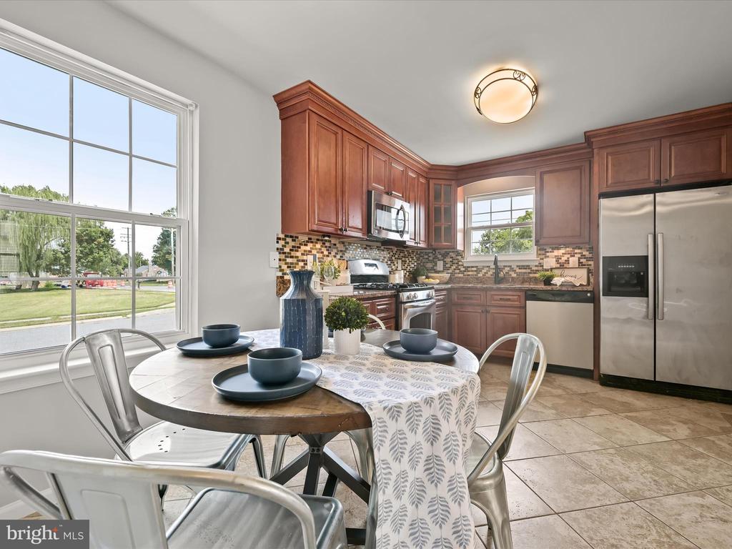 Kitchen with cherry cabinets and stainless steel appliances, with a dining table beside a large window.