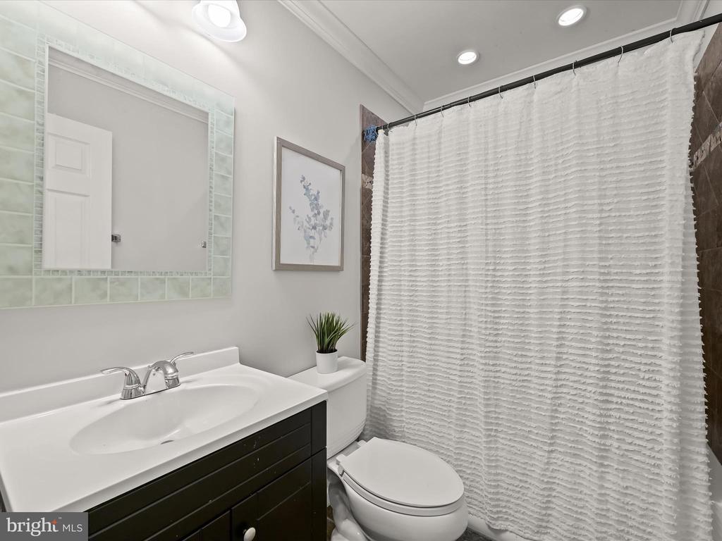 Bathroom with a dark vanity, white sink, and textured shower curtain.