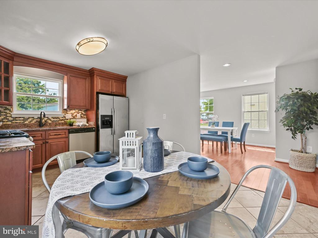 Kitchen and dining area with reddish wood cabinets, stainless steel refrigerator, and a round table set with blue bowls.