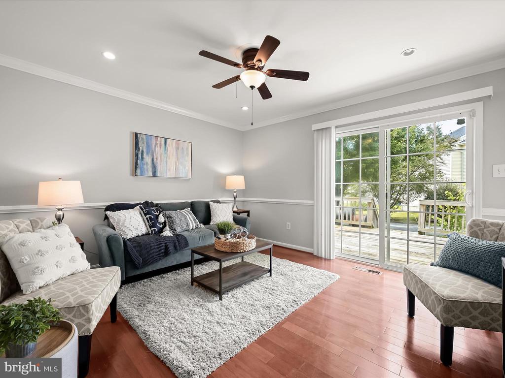 Living room with a teal sofa, patterned armchairs, and sliding glass doors opening to a deck.