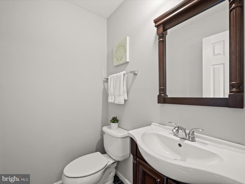Bathroom with a white sink and toilet beneath a dark wood-framed mirror.