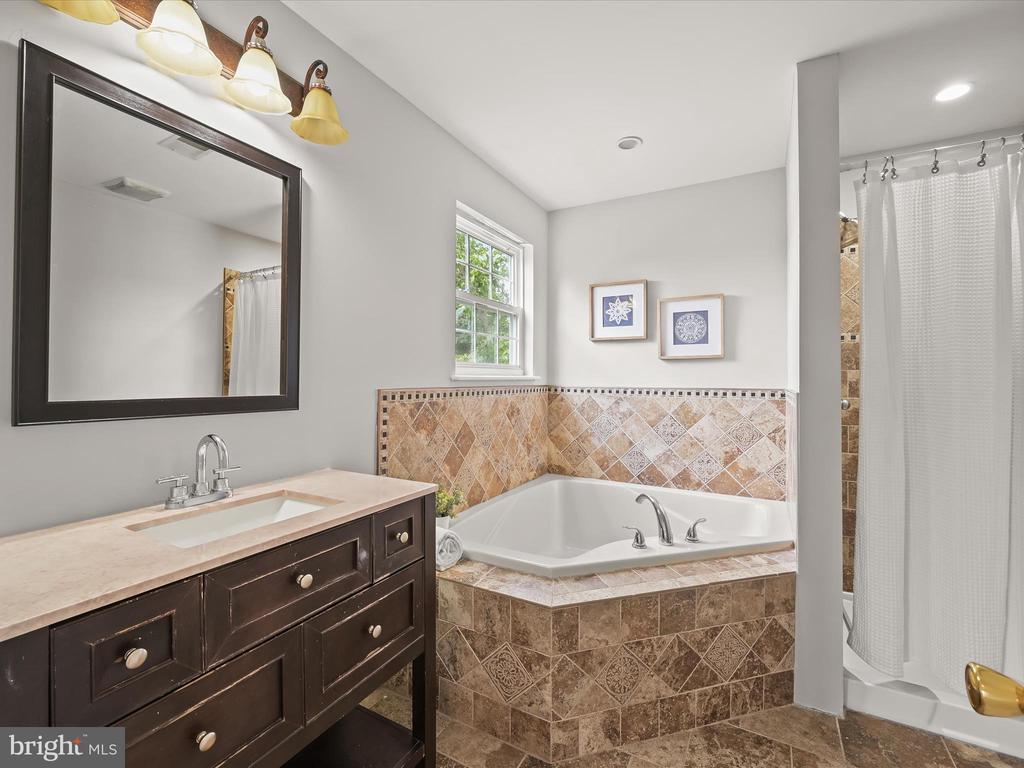 Bathroom with a dark wood vanity, tiled corner soaking tub, and separate curtained shower.