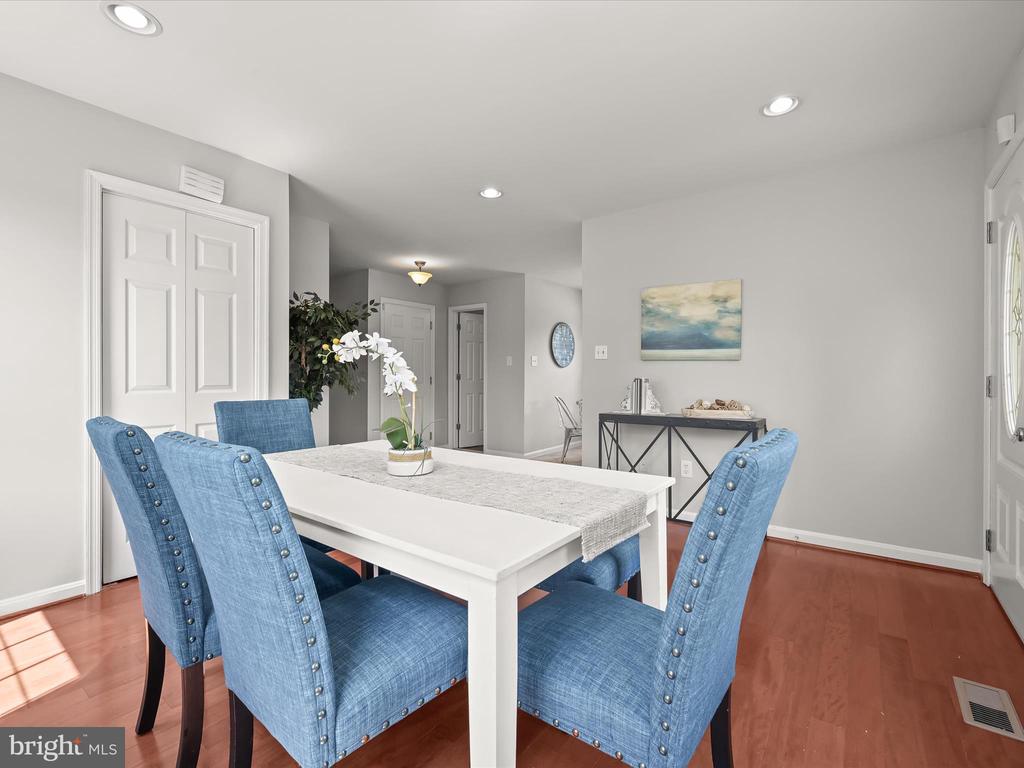 Dining room with a white table, blue chairs, and reddish hardwood floors.