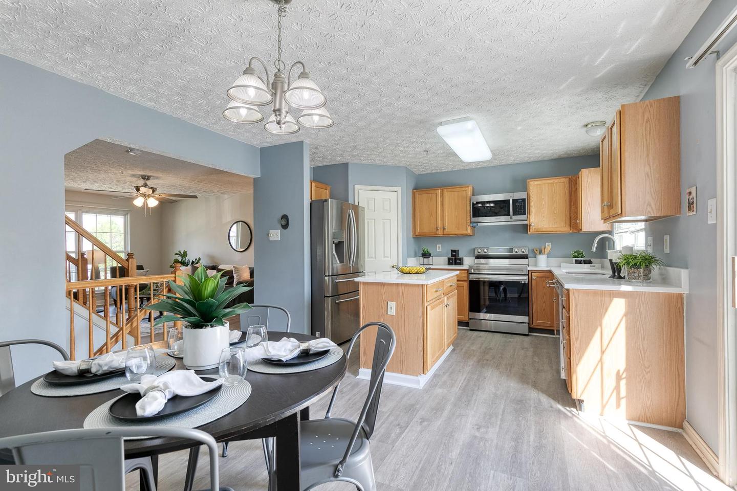 Kitchen and dining area with light wood cabinets, stainless steel appliances, and a set table.