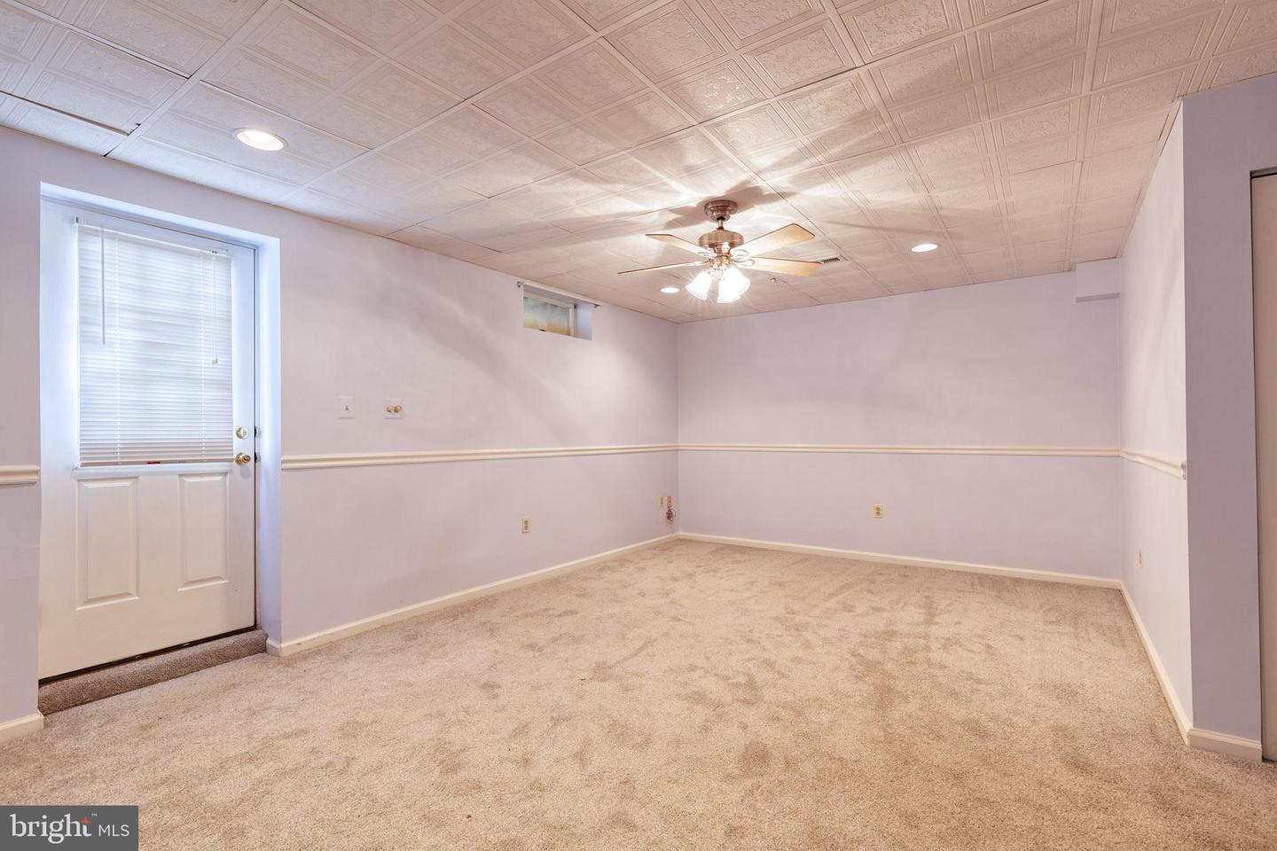 Empty carpeted room with a ceiling fan and a door with a window blind.