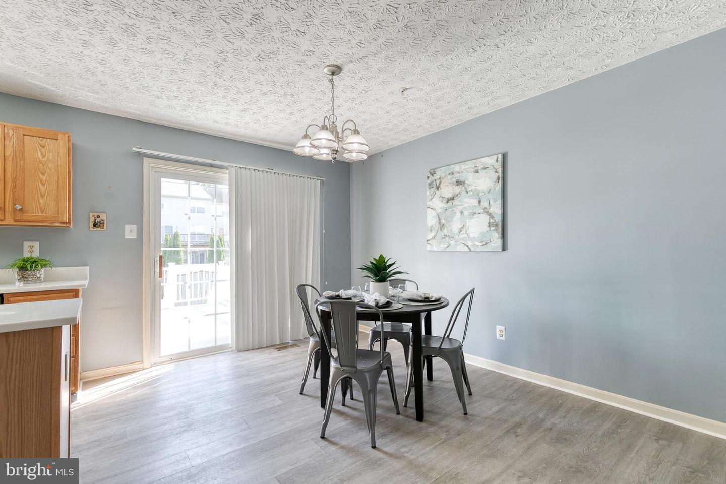 Dining area with a round table, metal chairs, and sliding glass door.