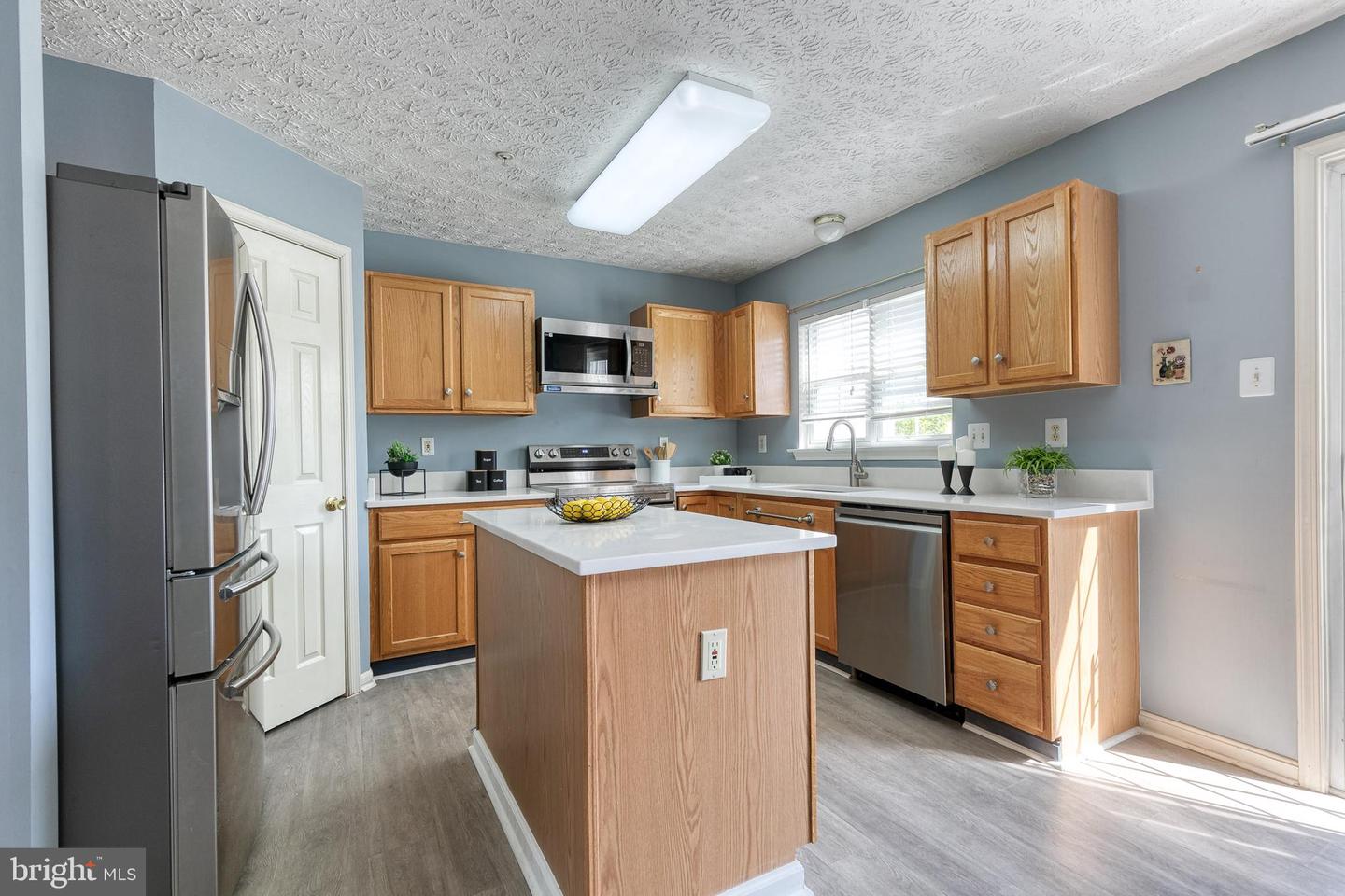 Kitchen with a central wood island, stainless steel appliances, and a window above the sink.