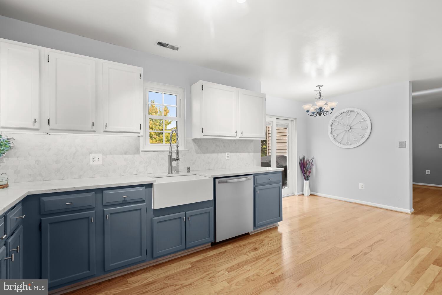 Kitchen with blue lower cabinets, white farmhouse sink, and hardwood floors.
