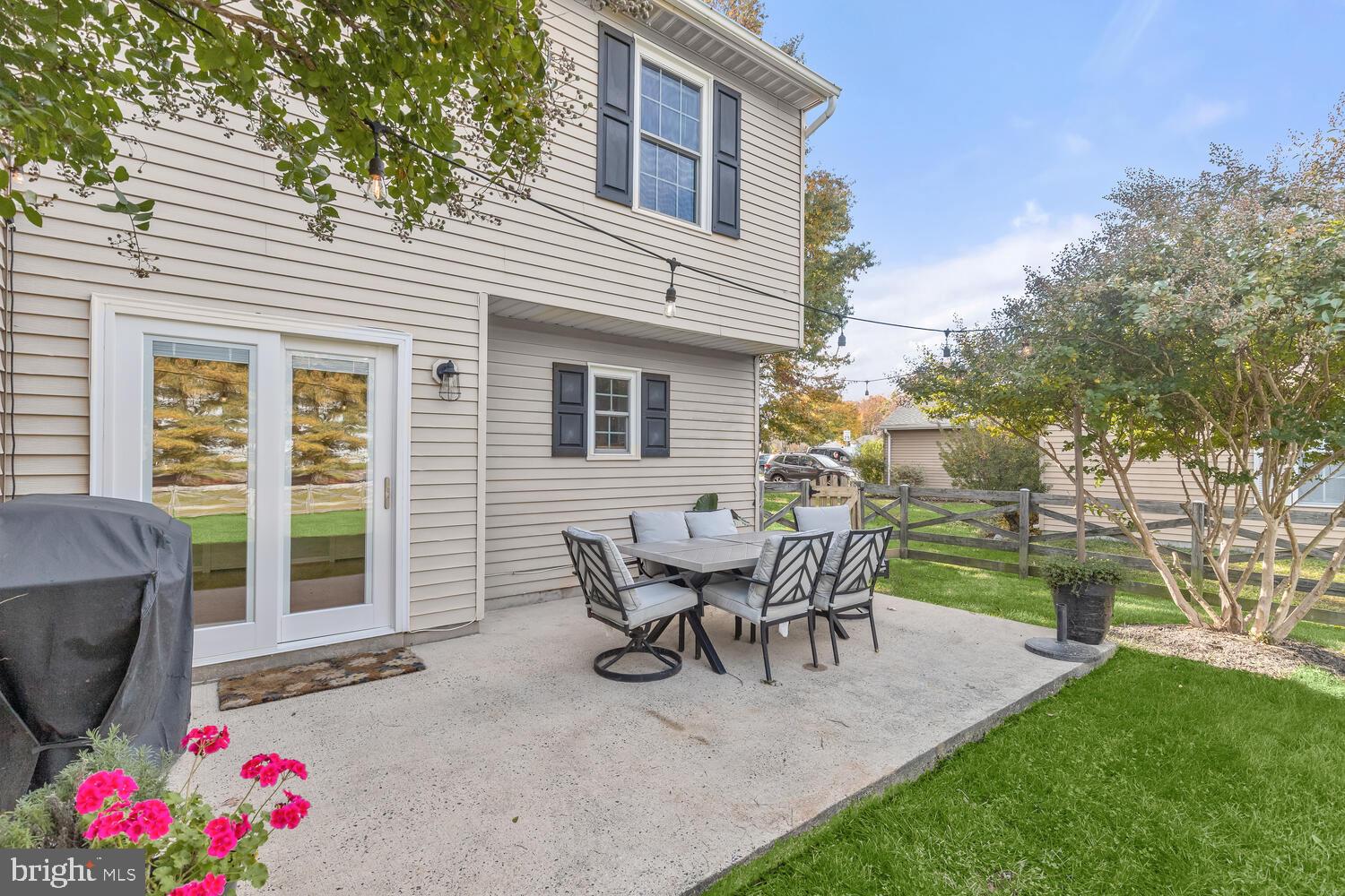 Back patio with outdoor dining set, sliding glass doors, and string lights.