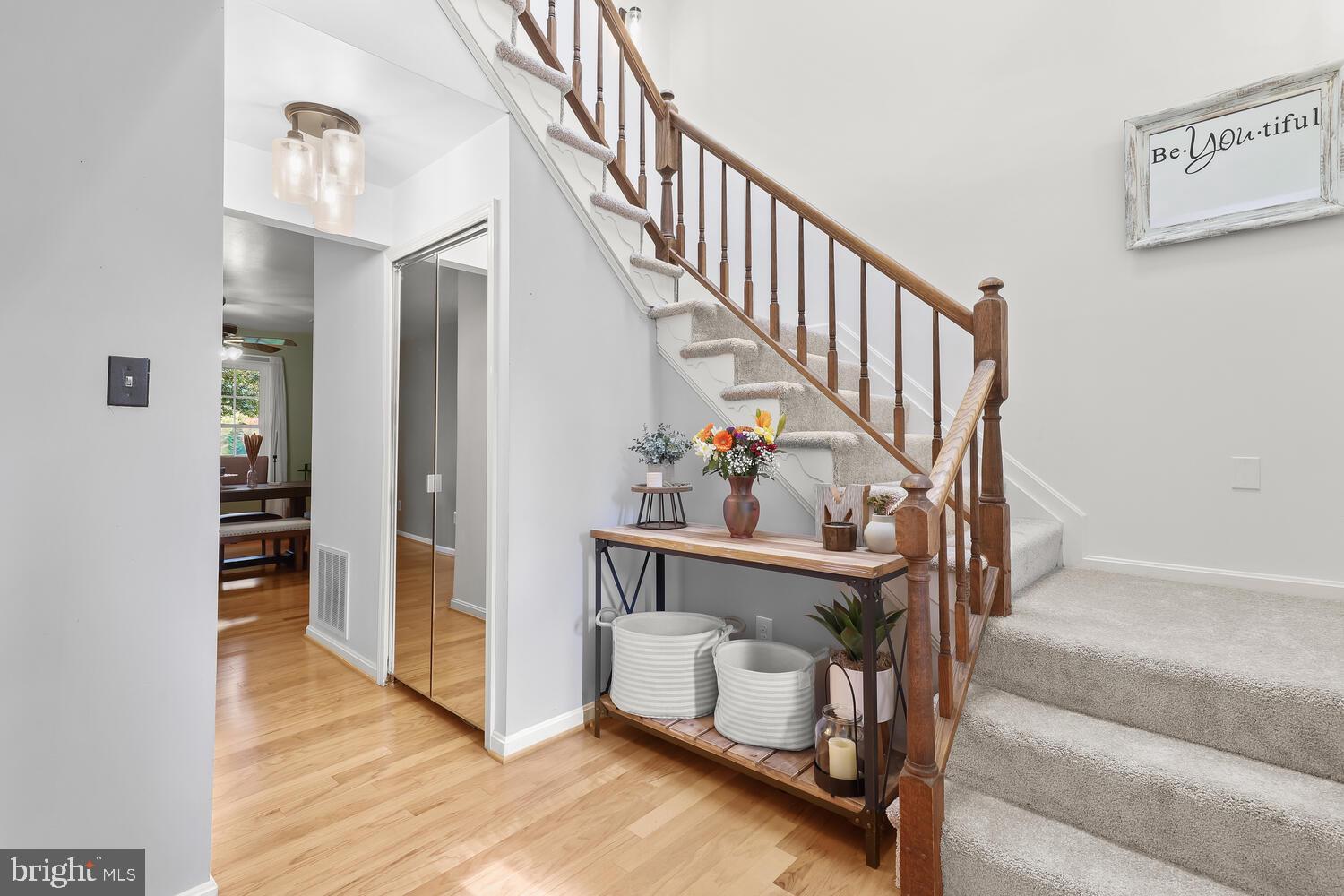 Foyer with a carpeted staircase, wooden banister, and flower-decorated console table.