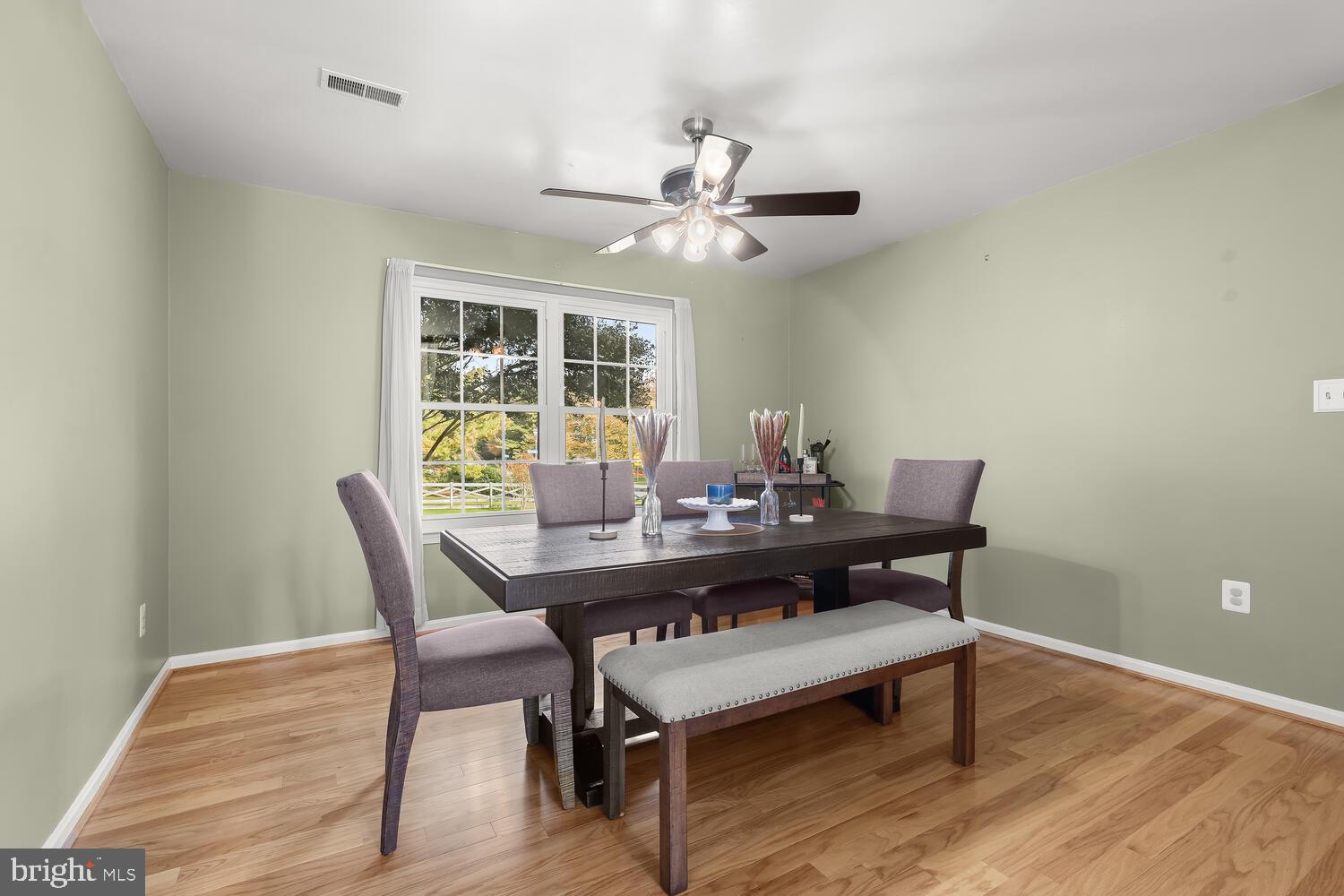 Dining room with a dark table, upholstered seating, hardwood floors, and a large window.