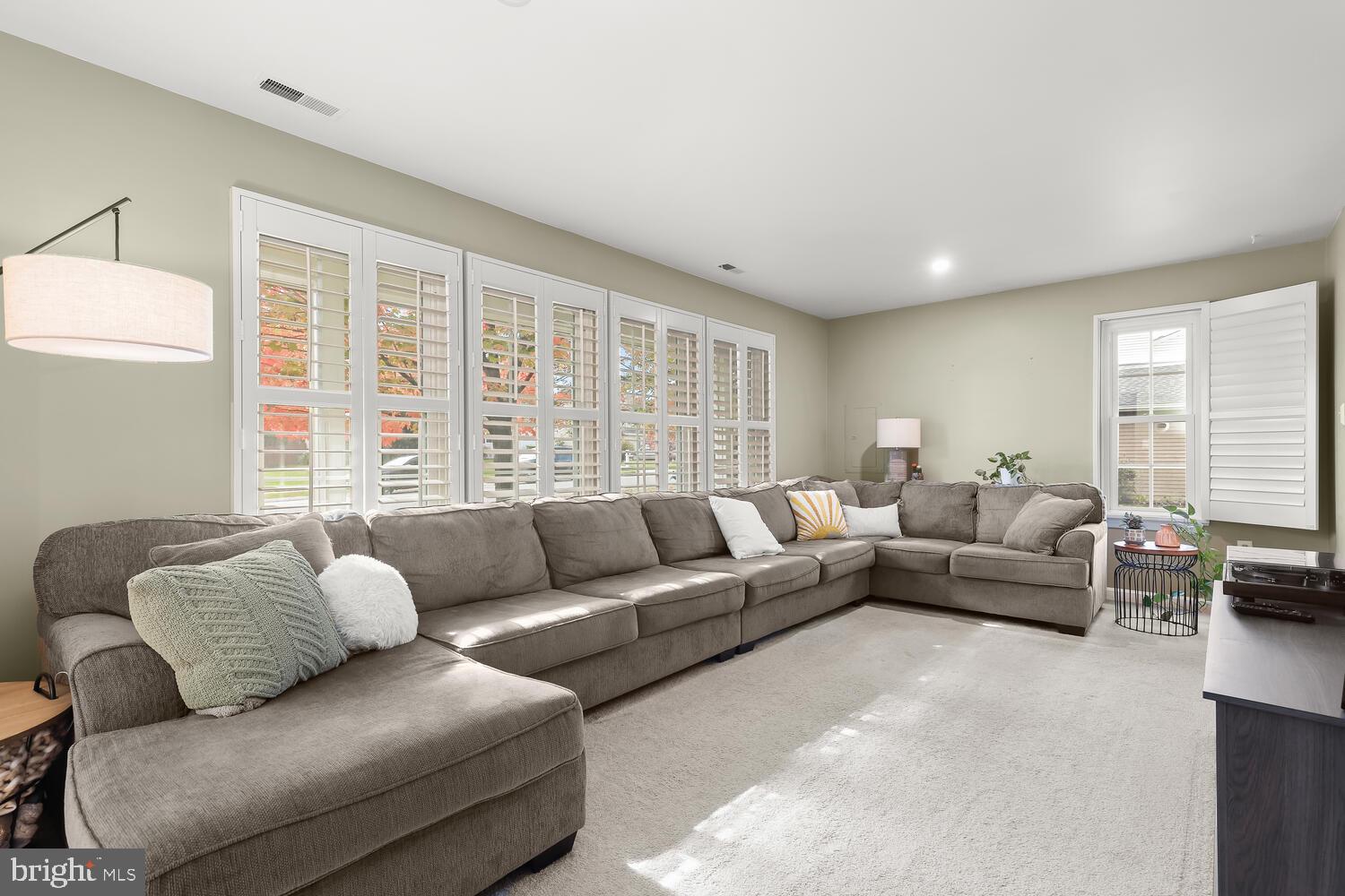 Living room with a large sectional sofa and plantation-shuttered windows.