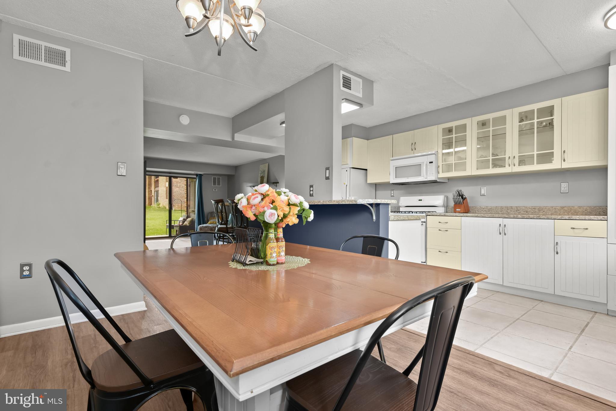 Kitchen and dining area with a wooden table, cream cabinets, and a dark blue breakfast bar.