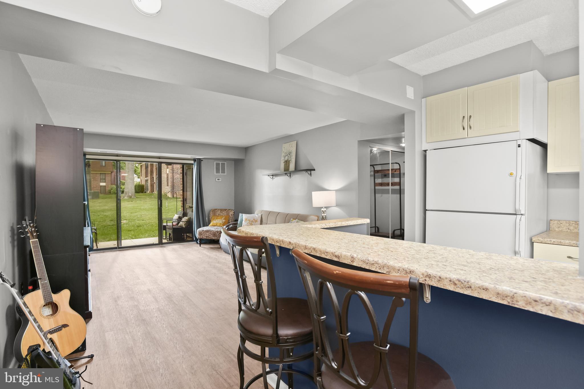Open-plan kitchen and living area with a granite breakfast bar and sliding doors to a grassy courtyard.