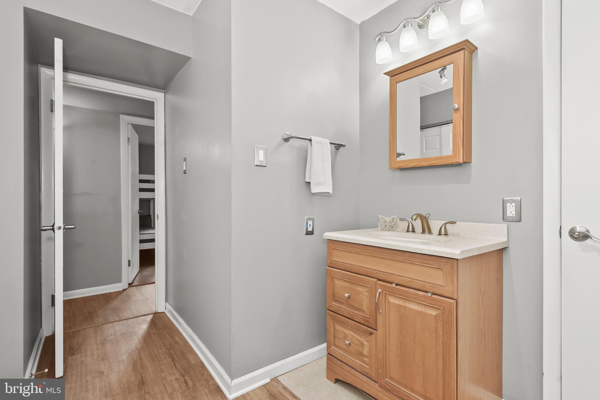 Bathroom with a wood vanity, framed mirror, and bright vanity lights.