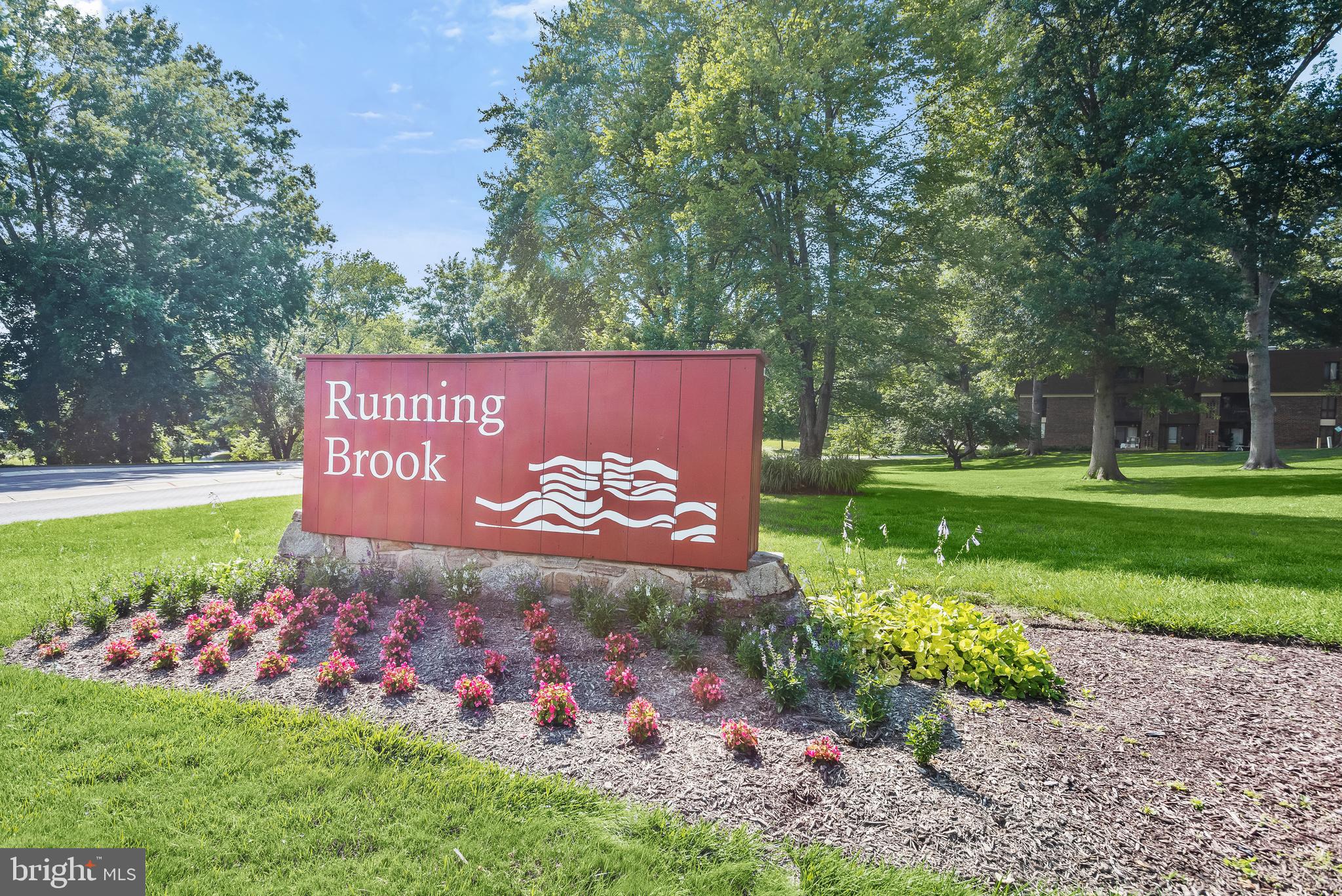 Running Brook community sign beside landscaped grounds and apartment buildings.