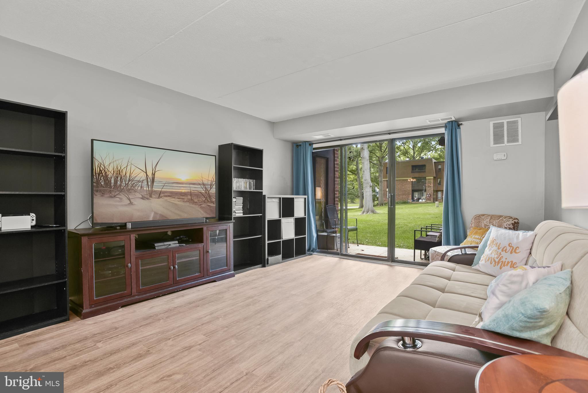 Living room with cream sofa, TV, and sliding glass doors opening to a lawn.