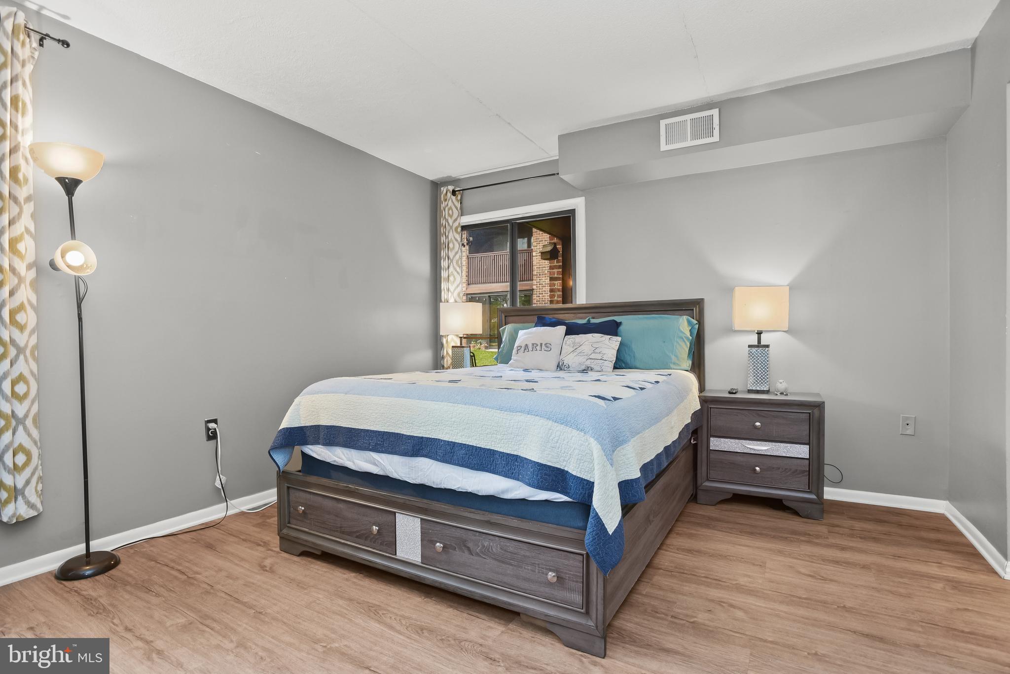 Bedroom with a dark wood bed, blue and white bedding, and a window behind the headboard.
