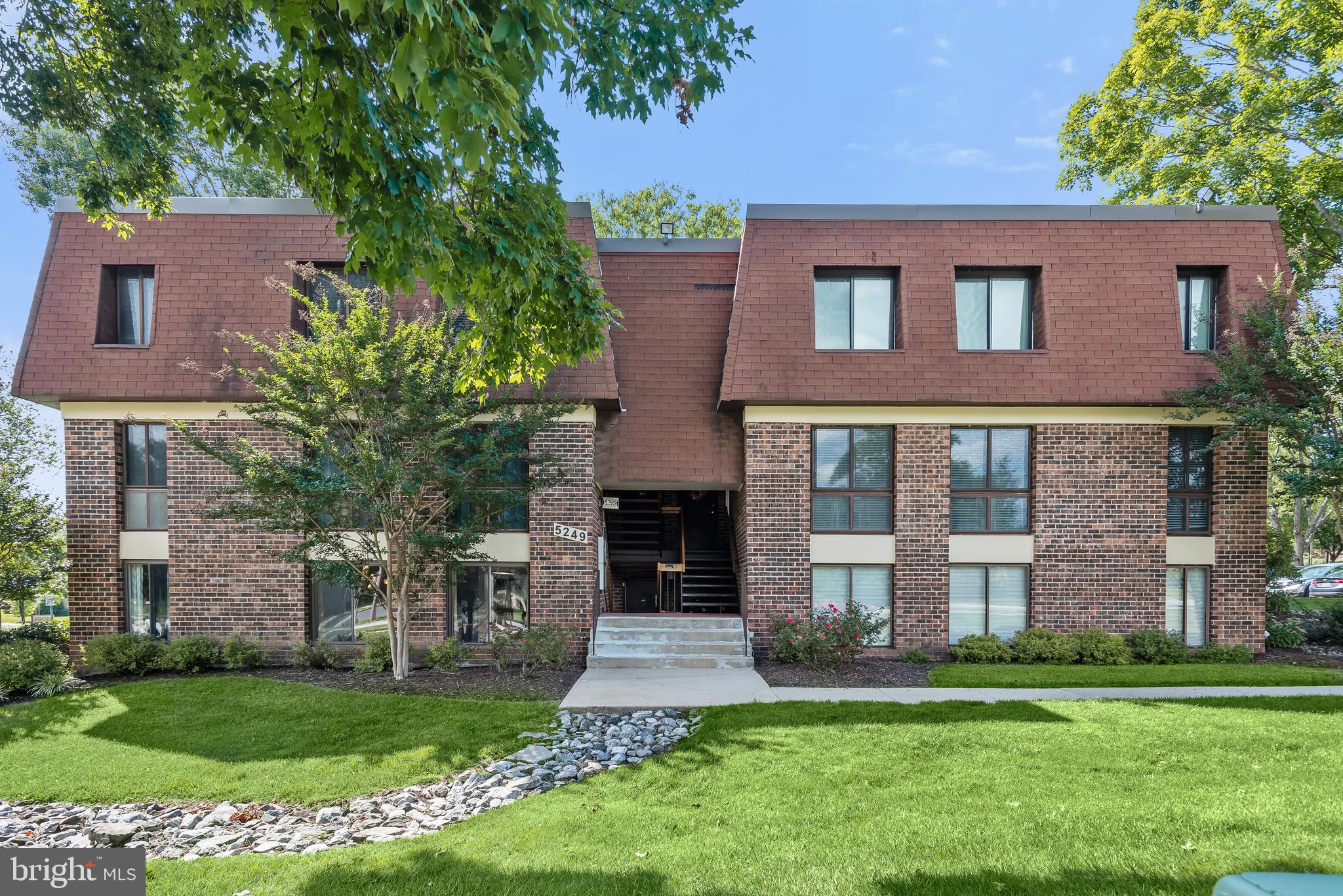 Brick condominium building at 5249 W Running Brook Road, with a recessed entrance and landscaped lawn.