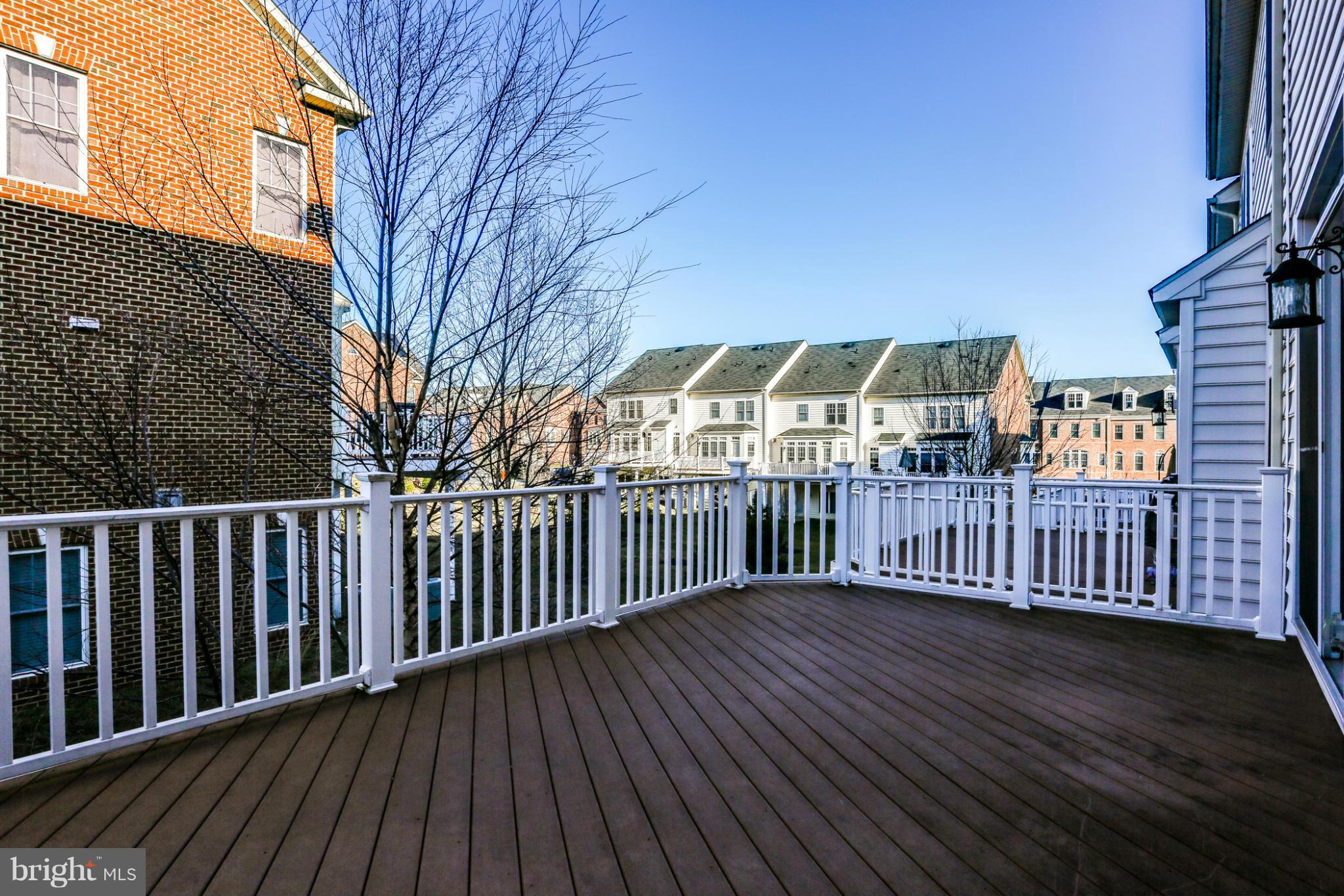 Elevated deck with white railings overlooking neighboring townhomes and leafless trees.