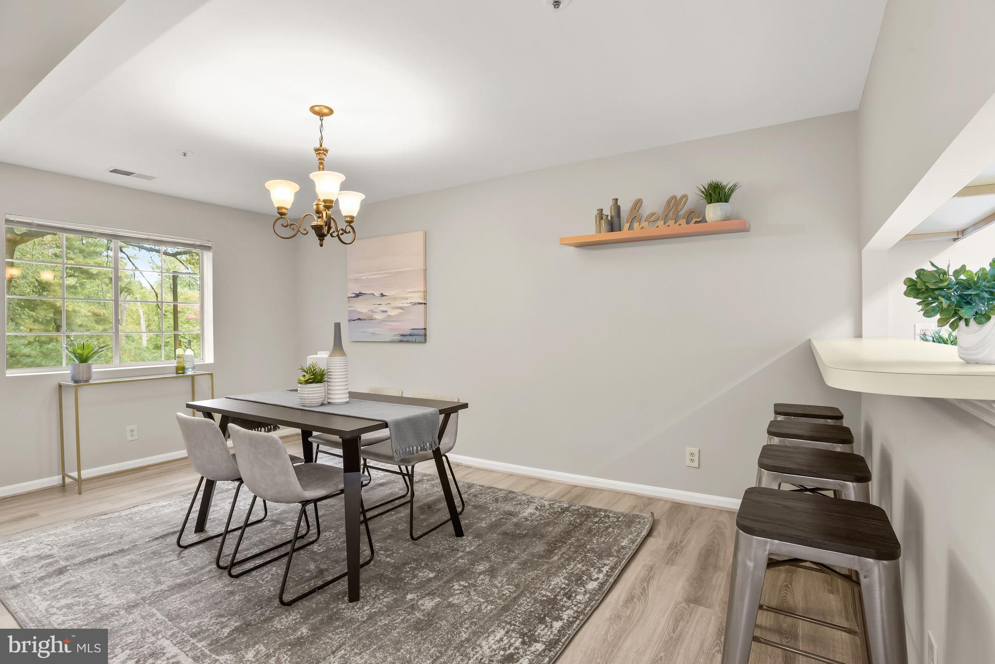 Dining room with a dark table, gray chairs, chandelier, and kitchen counter stools.