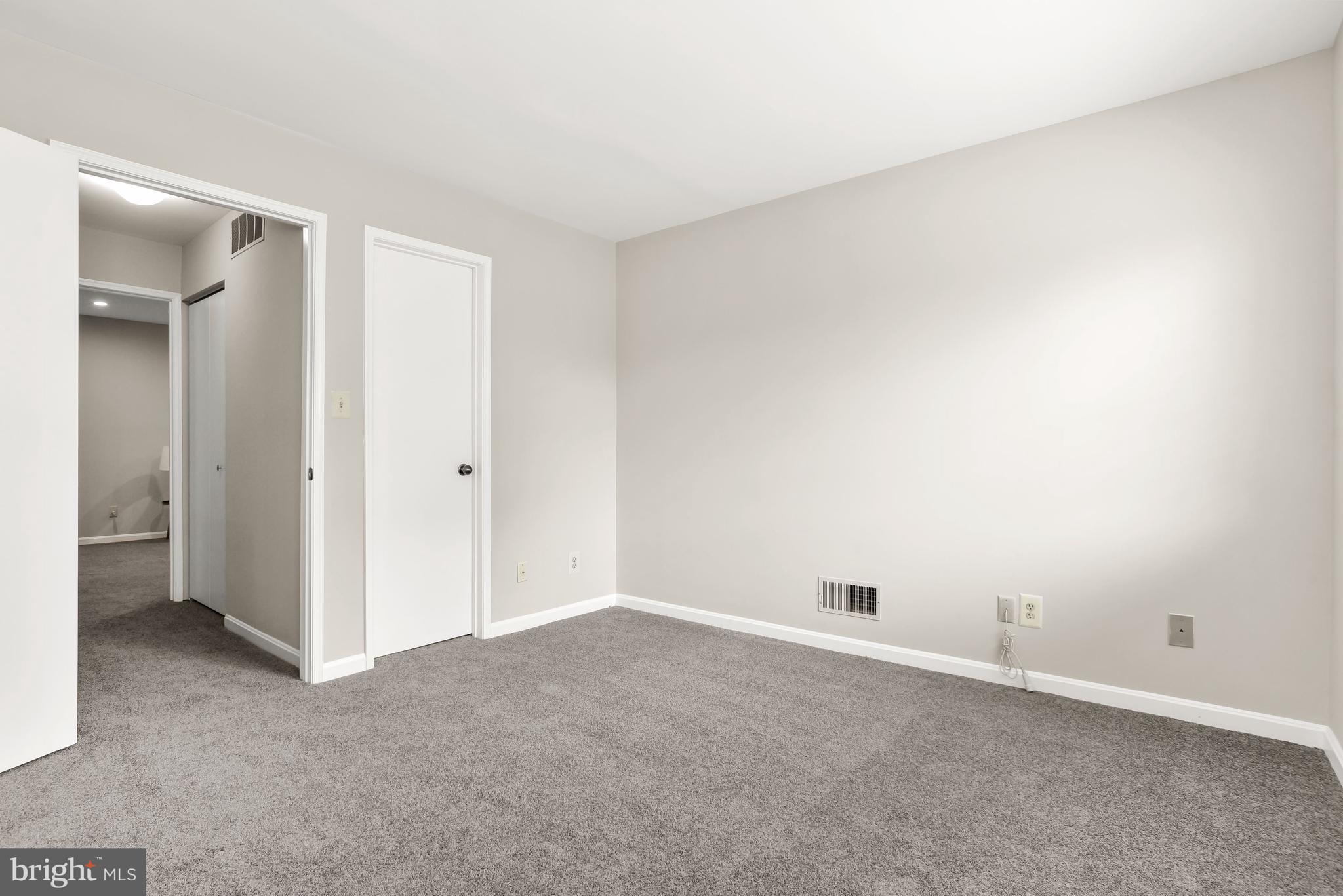 Empty carpeted room with neutral walls and an open doorway to the hall.