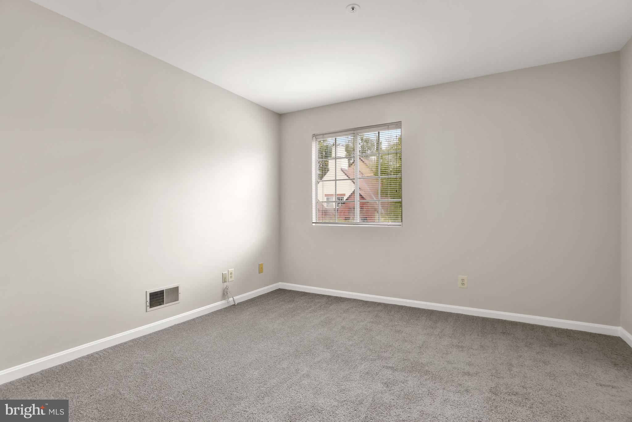 Empty carpeted room with neutral walls and a window with blinds.