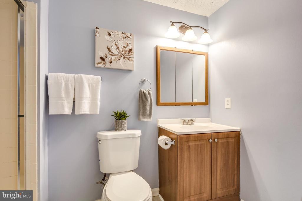 Bathroom with a wood vanity, framed mirror, toilet, and light gray walls.